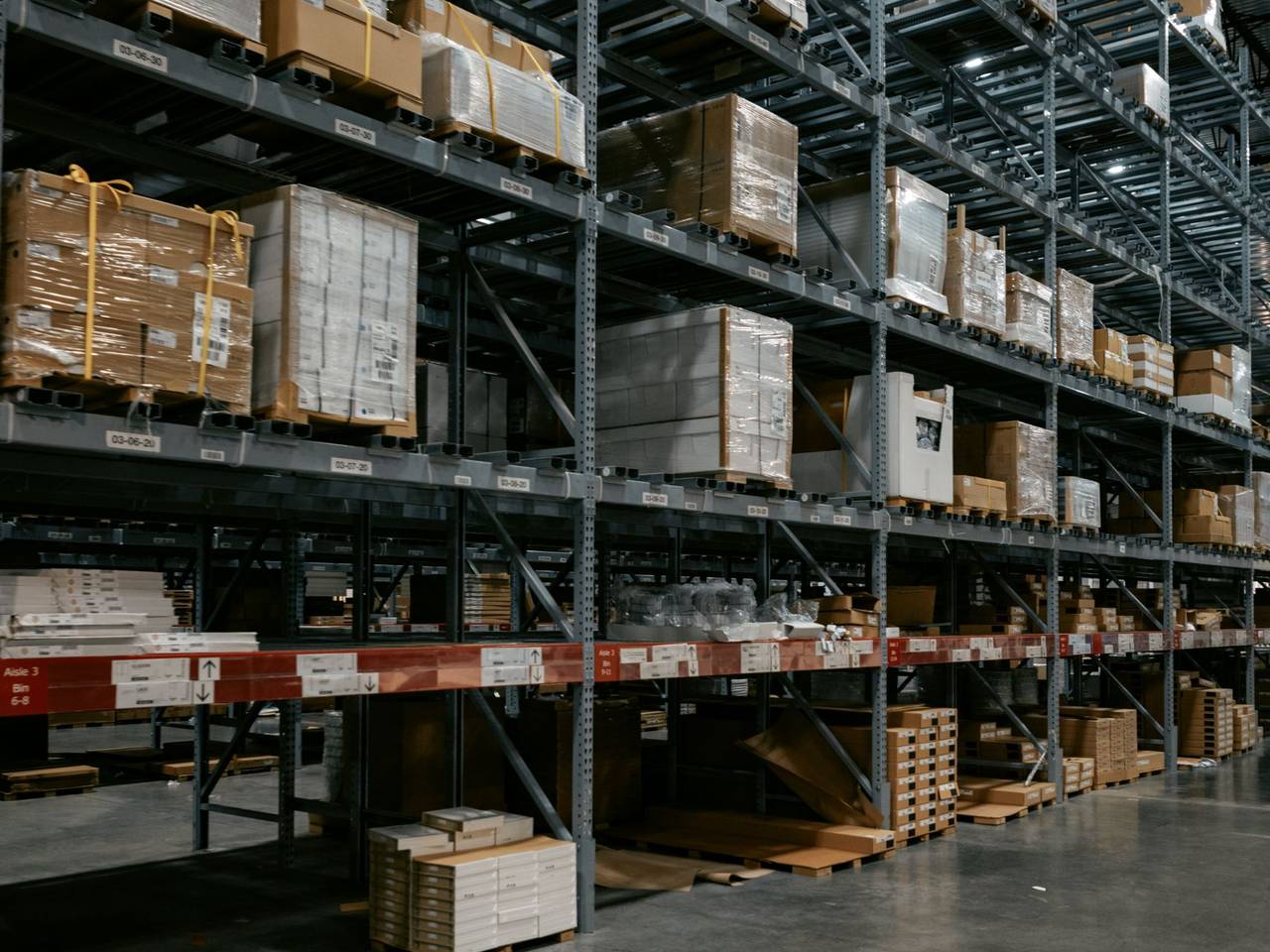 Bodega con estanterías altas y pallets de mercadería