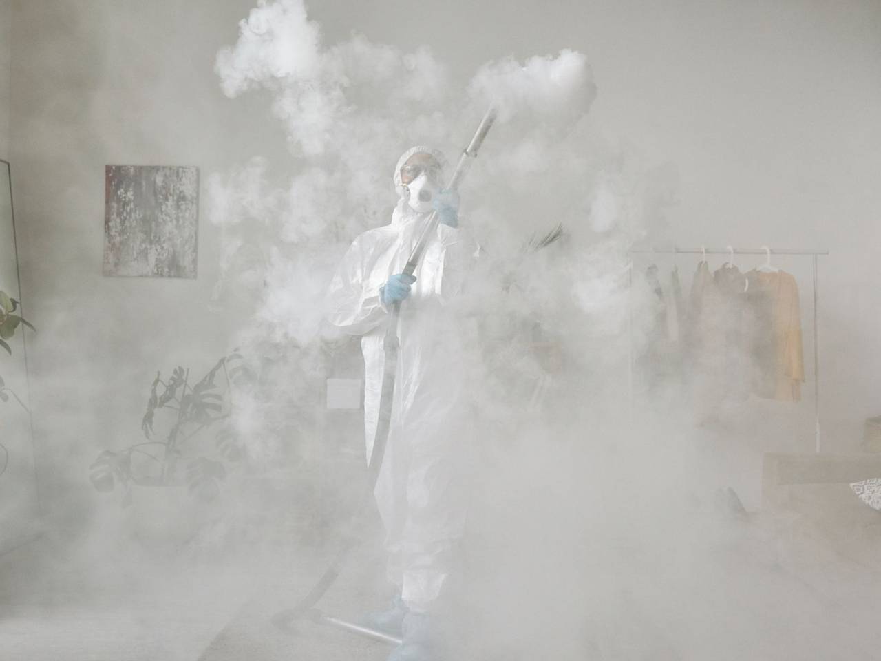 Persona con traje de protección sanitizando un ambiente con nebulización en frío